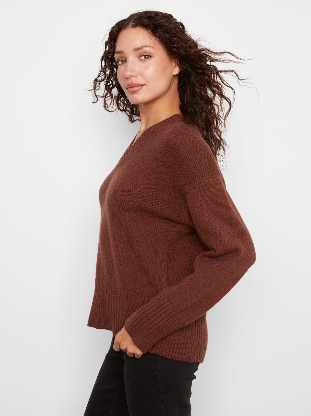 Woman wearing a brown sweater against a white background