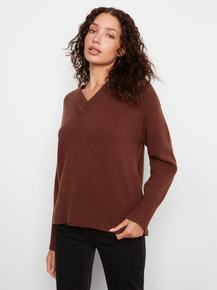 Woman wearing a brown sweater against a white background