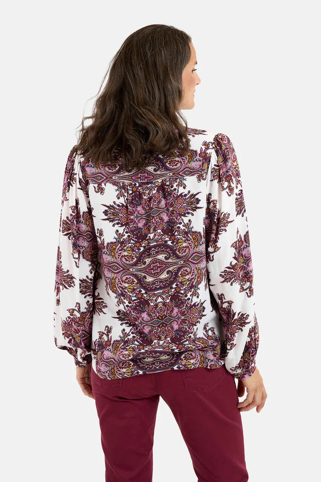 Woman wearing a patterned blouse and red pants on a white background