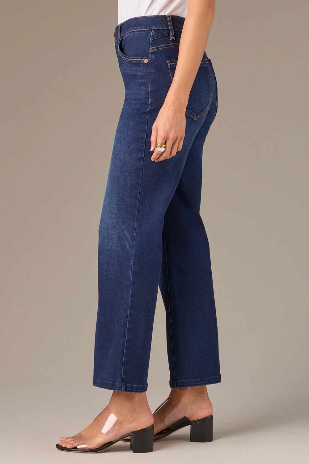 Person wearing blue jeans on a neutral background