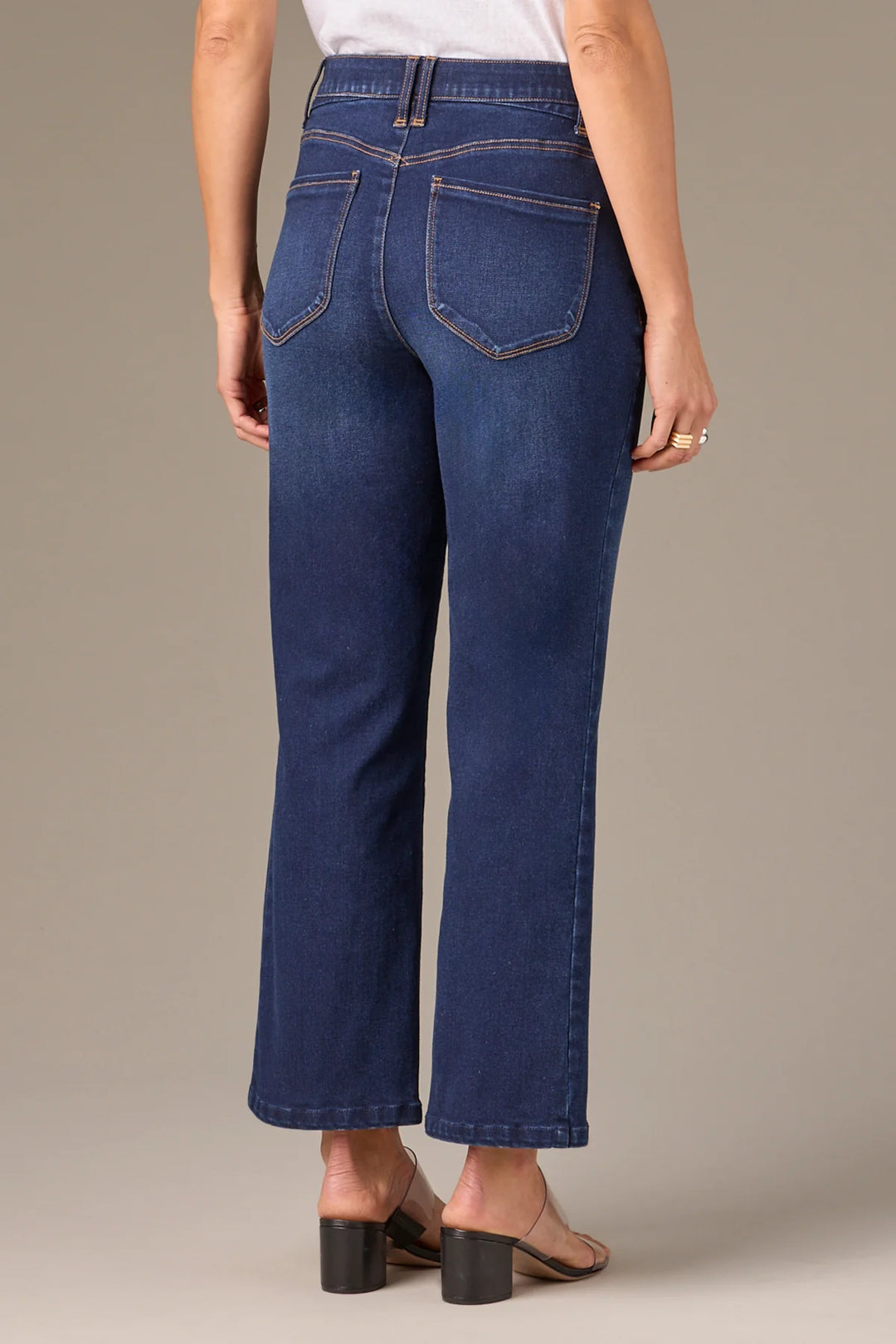 Person wearing blue jeans on a neutral background