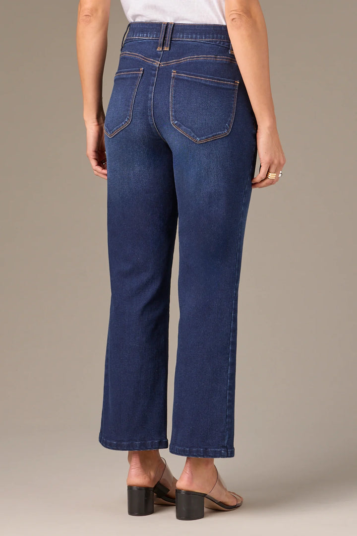 Person wearing blue jeans on a neutral background