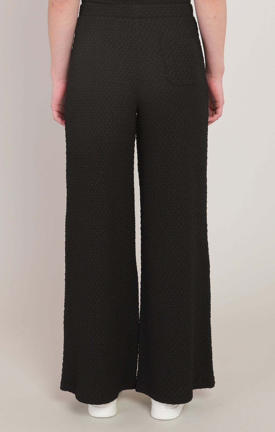 Black textured wide-leg pants worn by a person on a plain background
