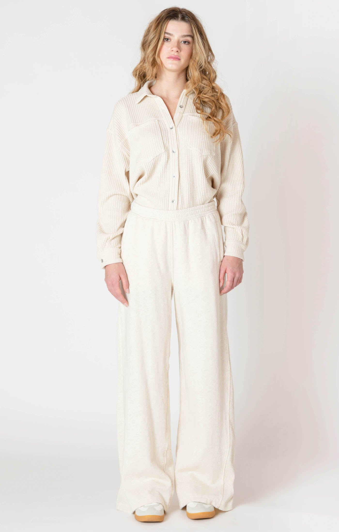 Woman wearing a cream-colored jumpsuit on a white background