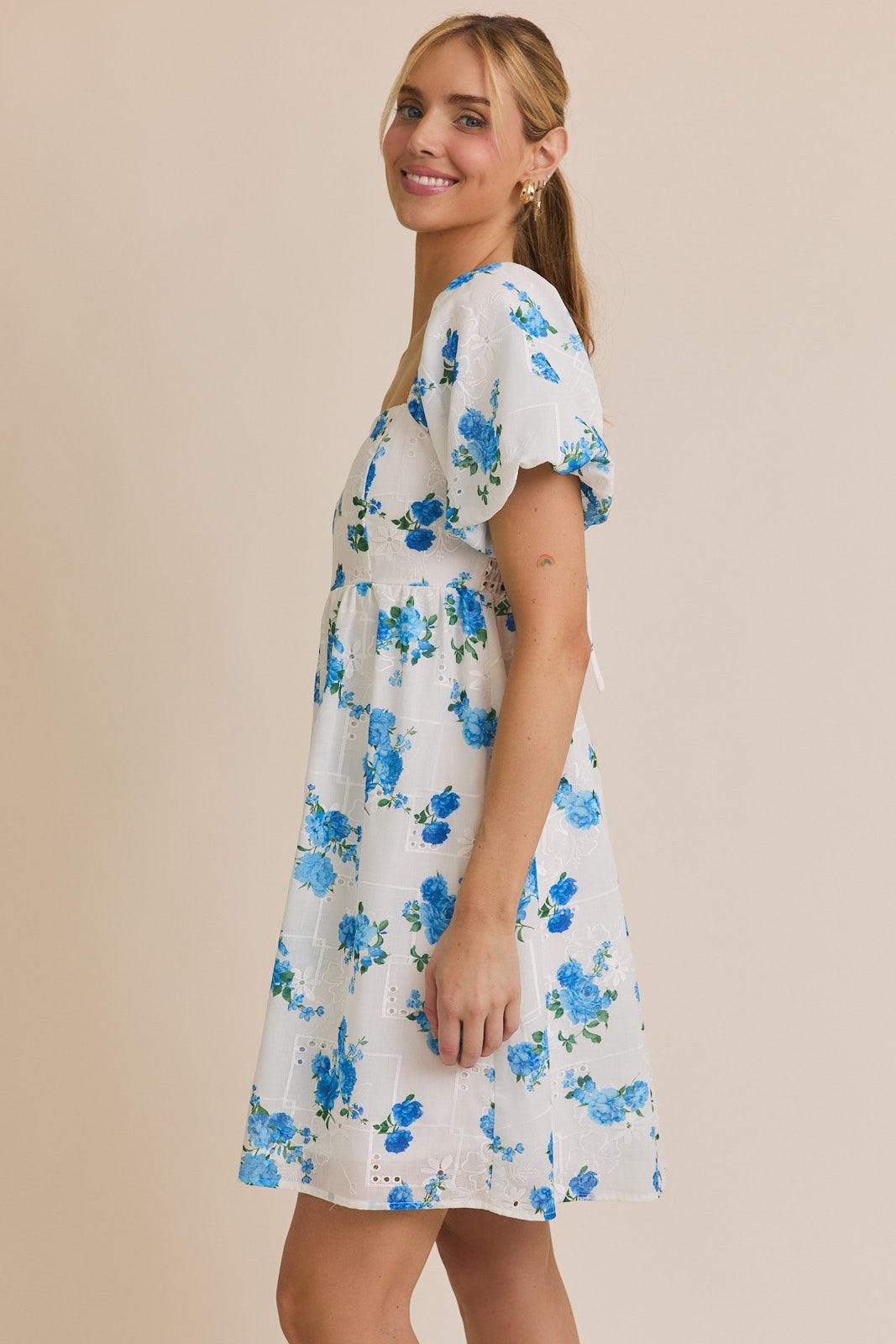 Woman wearing a white dress with blue floral pattern on a beige background