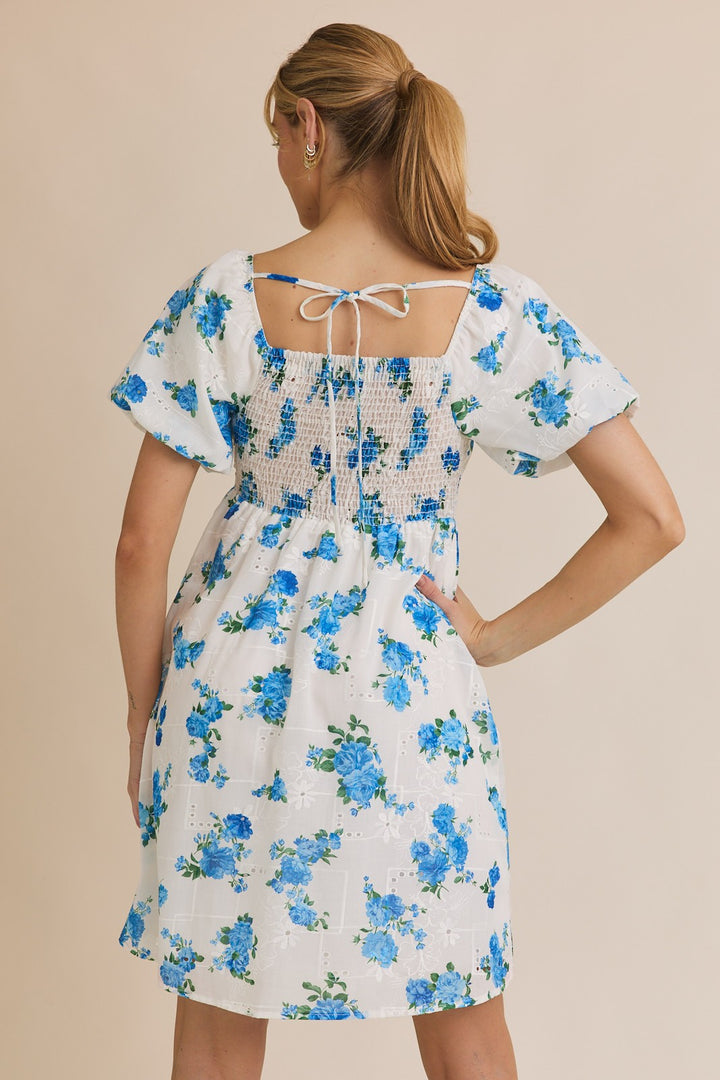 Woman wearing a white dress with blue floral pattern on a beige background
