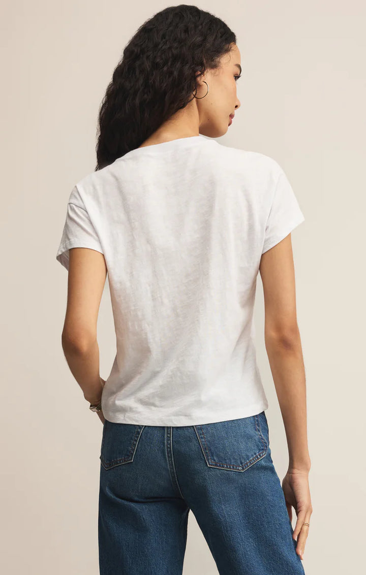 Person wearing a white t-shirt and blue jeans against a beige background