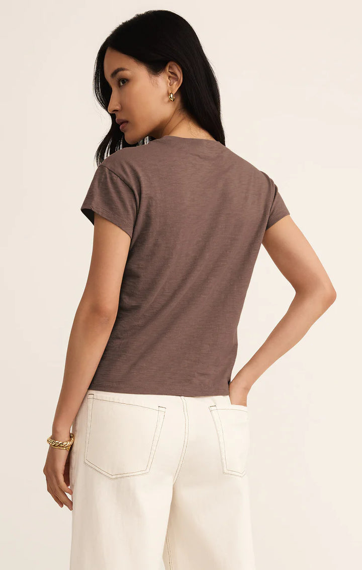 Woman wearing a brown t-shirt and white pants on a beige background