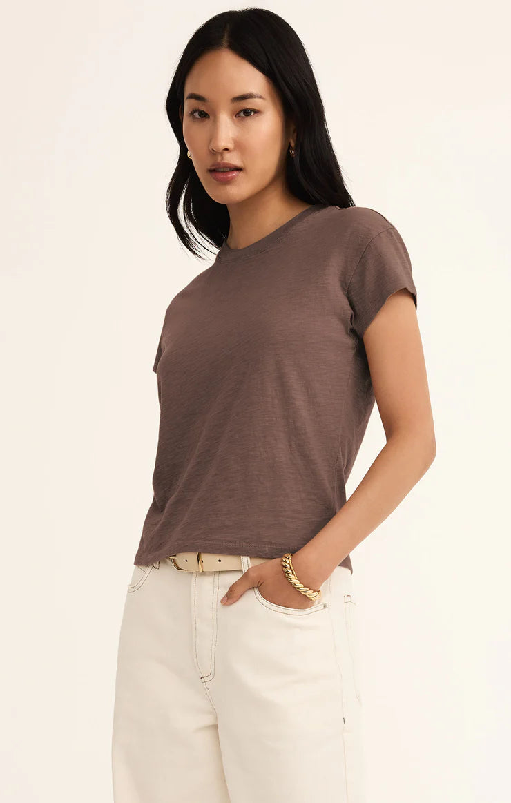 Woman wearing a brown t-shirt and white pants on a beige background