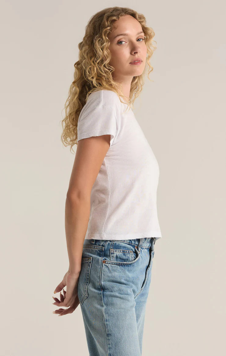 Woman wearing a white t-shirt and blue jeans against a plain background