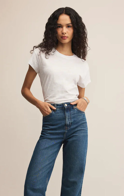 Woman wearing a white t-shirt and blue jeans on a beige background