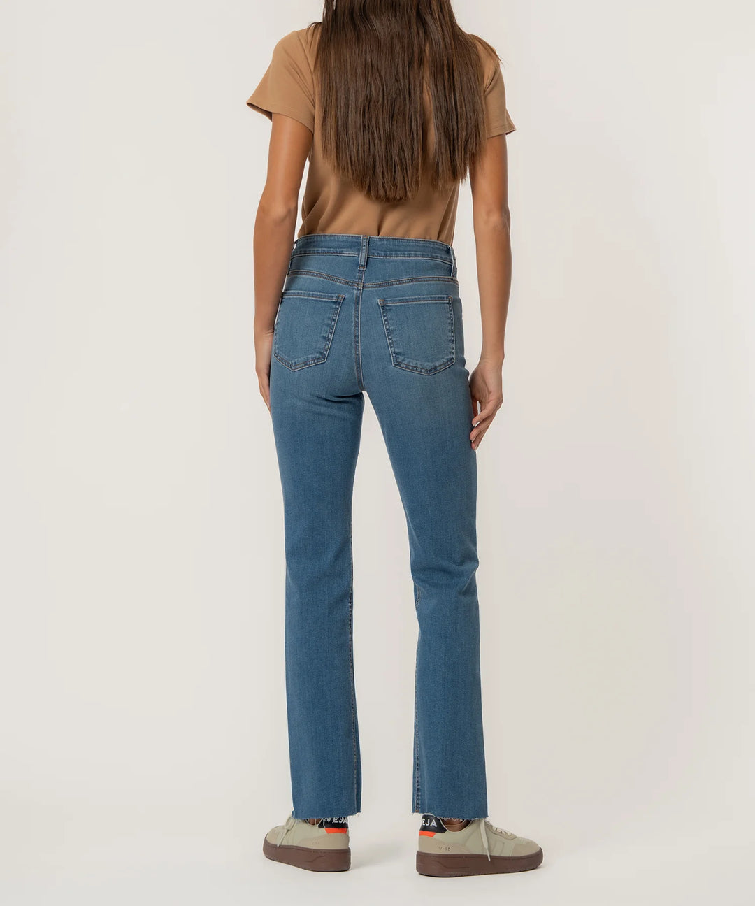 Person wearing blue jeans and a brown shirt on a white background