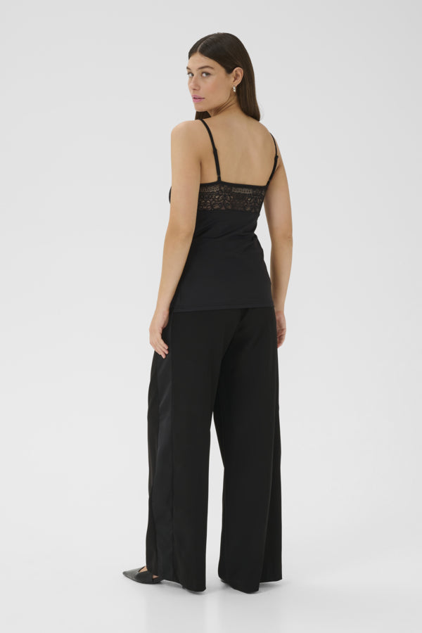 Woman wearing a black lace top and wide-leg pants on a white background
