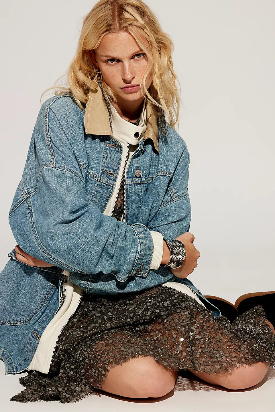 Woman wearing a denim jacket and black mesh skirt on a white background