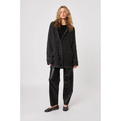 Woman wearing a dark gray cardigan and black pants on a white background