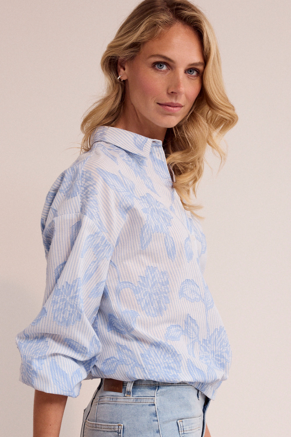Woman wearing a light blue patterned shirt with a plain background