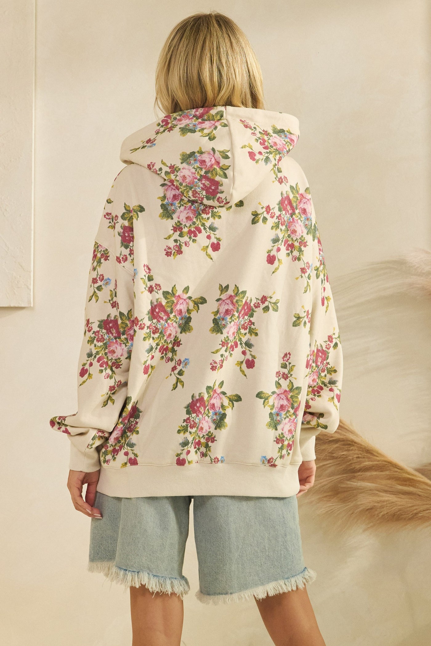 Person wearing a floral-patterned cardigan with a neutral background