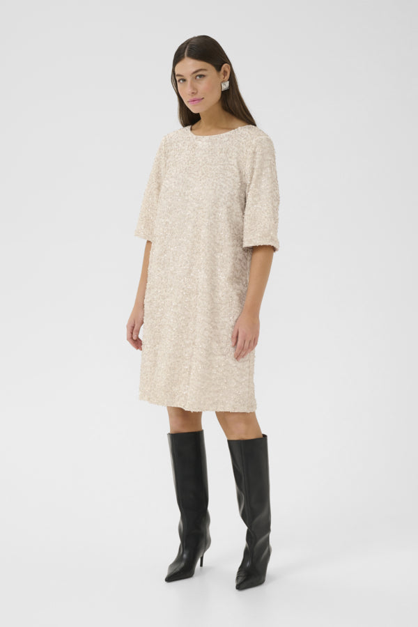 Woman wearing a beige dress and black knee-high boots on a white background