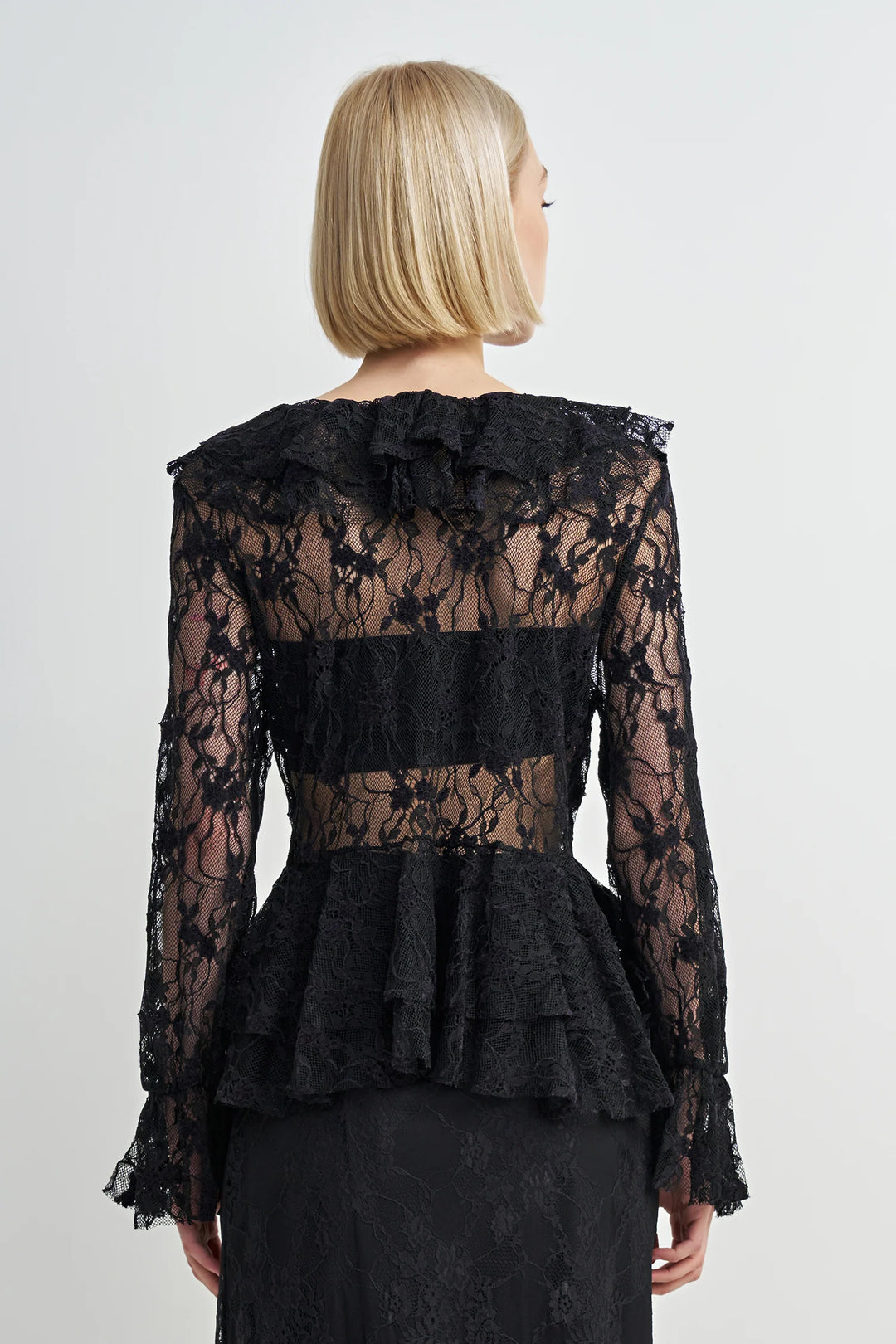 Black lace peplum top worn by a person on a white background