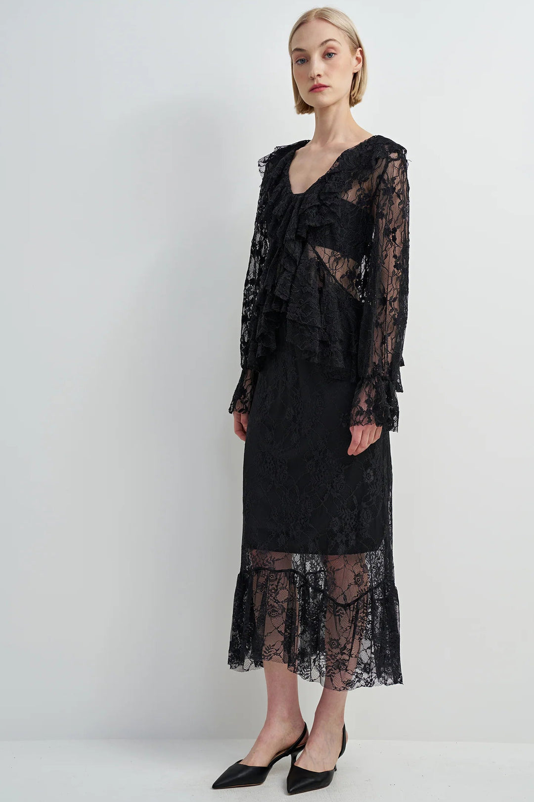 Woman wearing a black lace dress against a white background