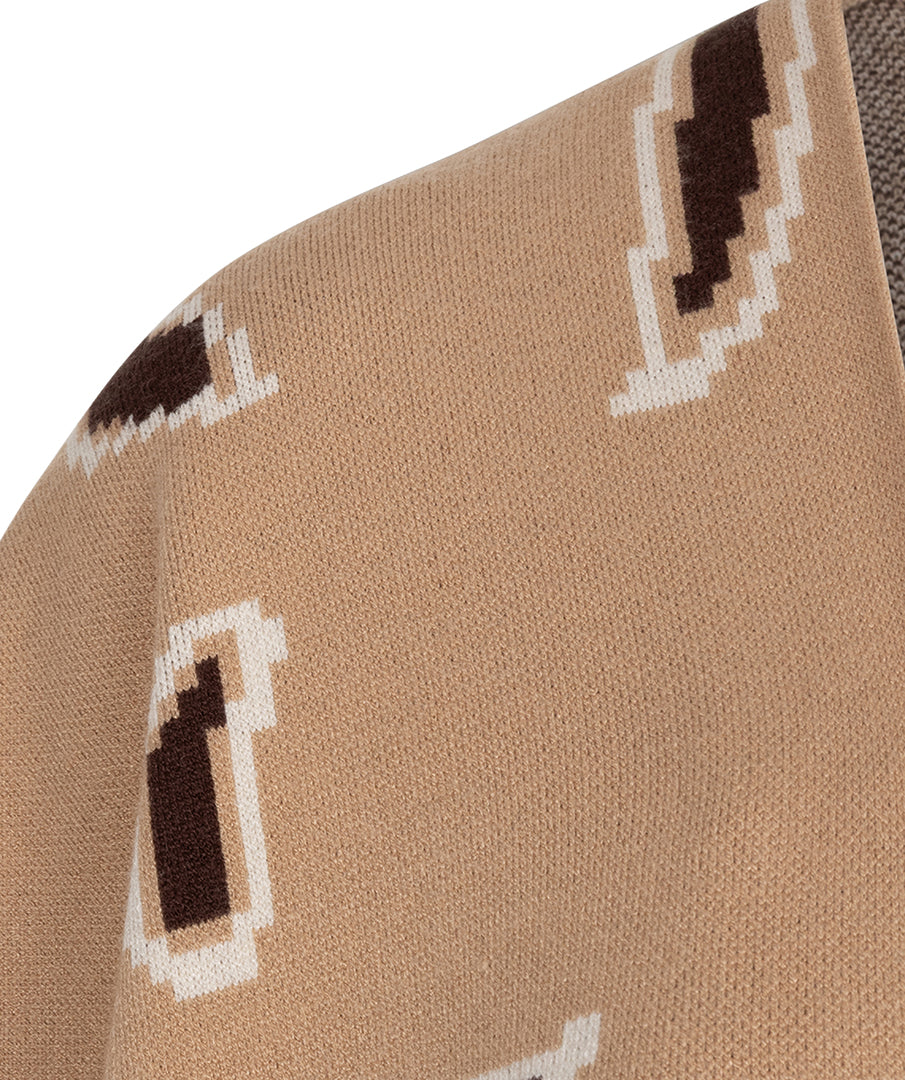 Close-up of a knit fabric with a repeating geometric pattern in beige, white, and dark brown on a white background.