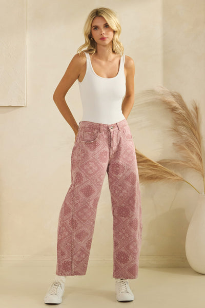 Woman wearing a white tank top and pink patterned pants against a beige background