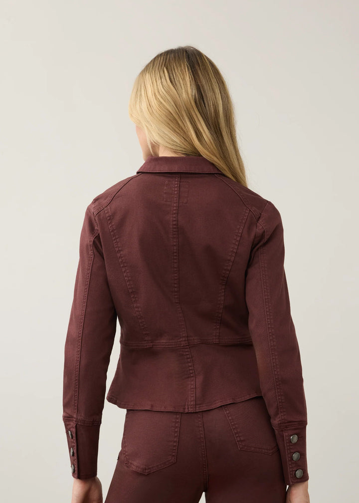 A woman viewed from the back wearing a dark burgundy cropped jacket and matching pants against a light gray studio background.
