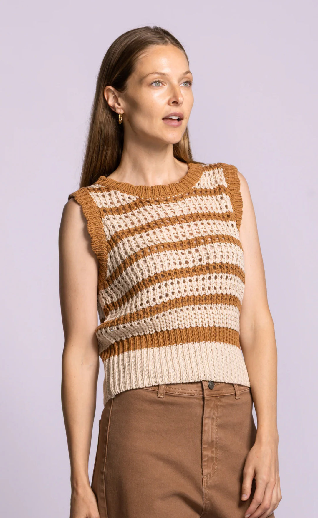 Woman wearing a sleeveless striped sweater against a light purple background