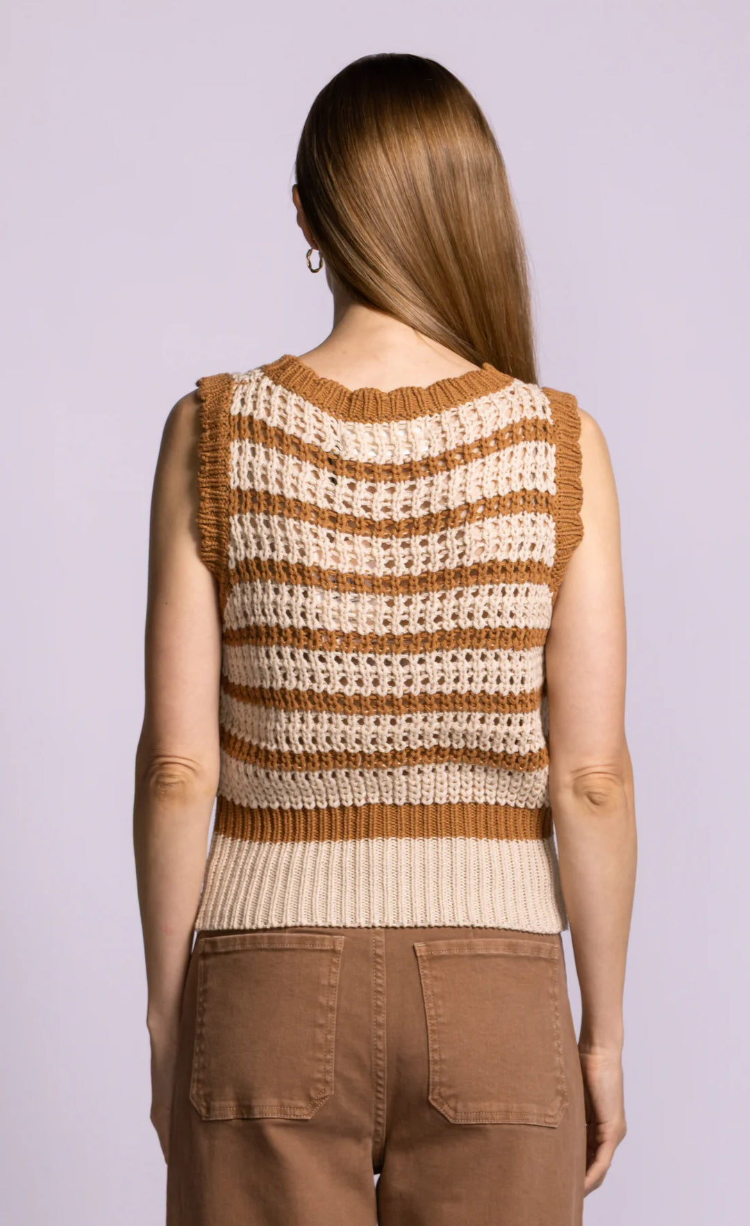 Woman wearing a brown and beige striped sleeveless sweater against a light purple background