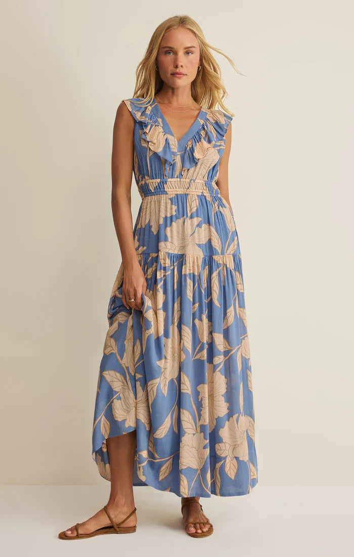 Woman wearing a blue and beige floral dress against a plain background