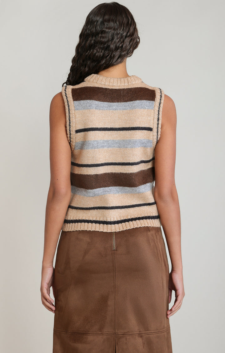 A woman shown from the back wearing a sleeveless knit sweater vest with horizontal stripes in beige, brown, black, and light blue, paired with a brown skirt, against a light gray studio background.
