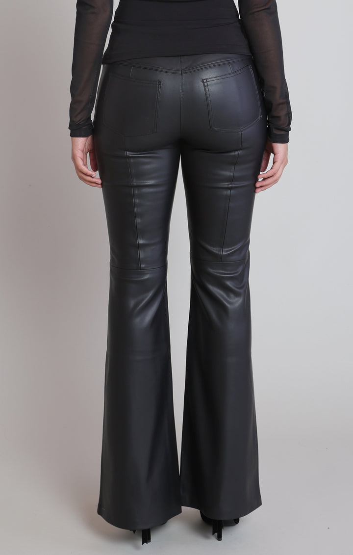 Black faux leather flare pants shown from the back on a model, featuring a smooth leather-like finish and side seam detailing, paired with a black sheer long-sleeve top.