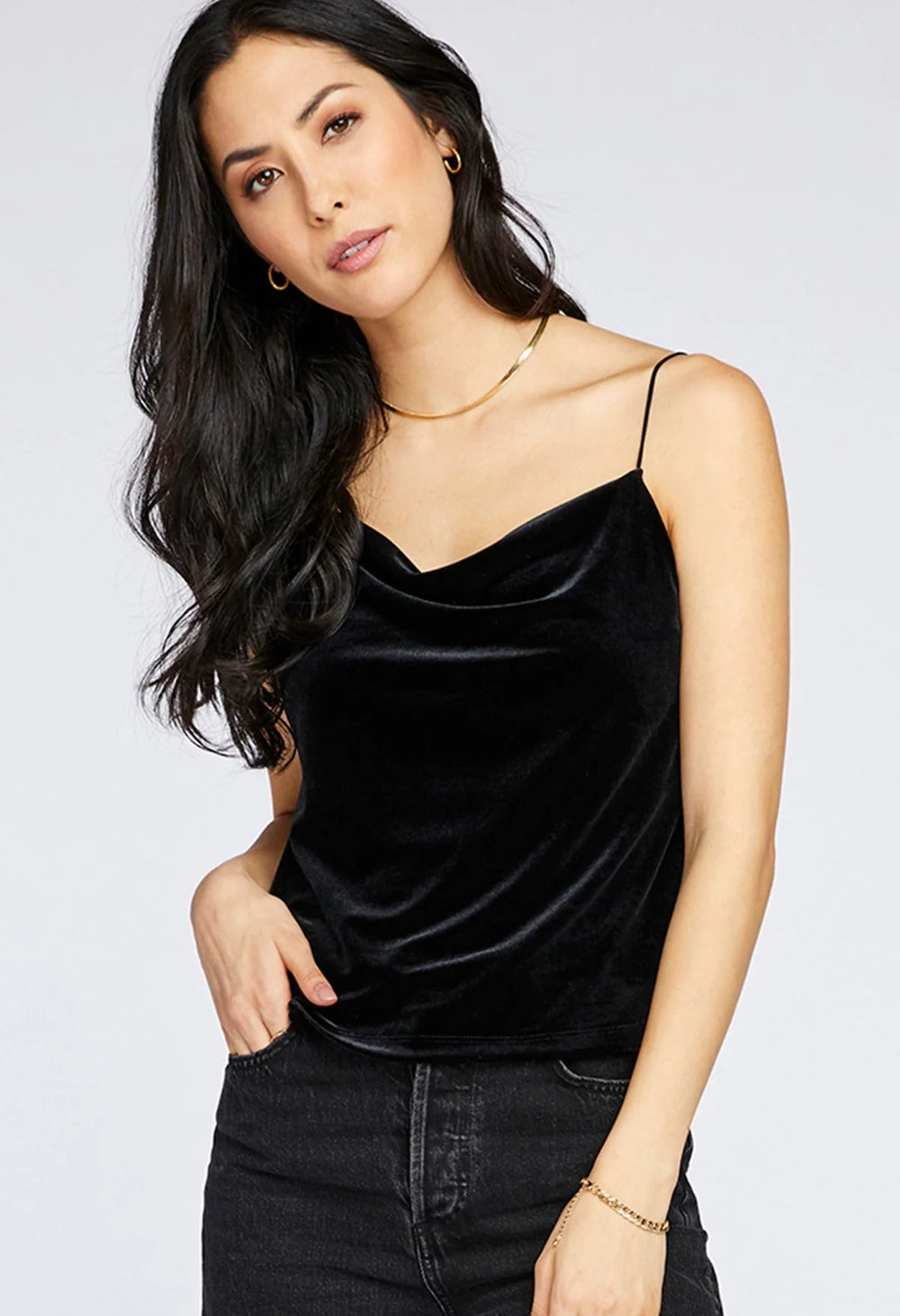 Woman wearing a black velvet top and black pants on a white background