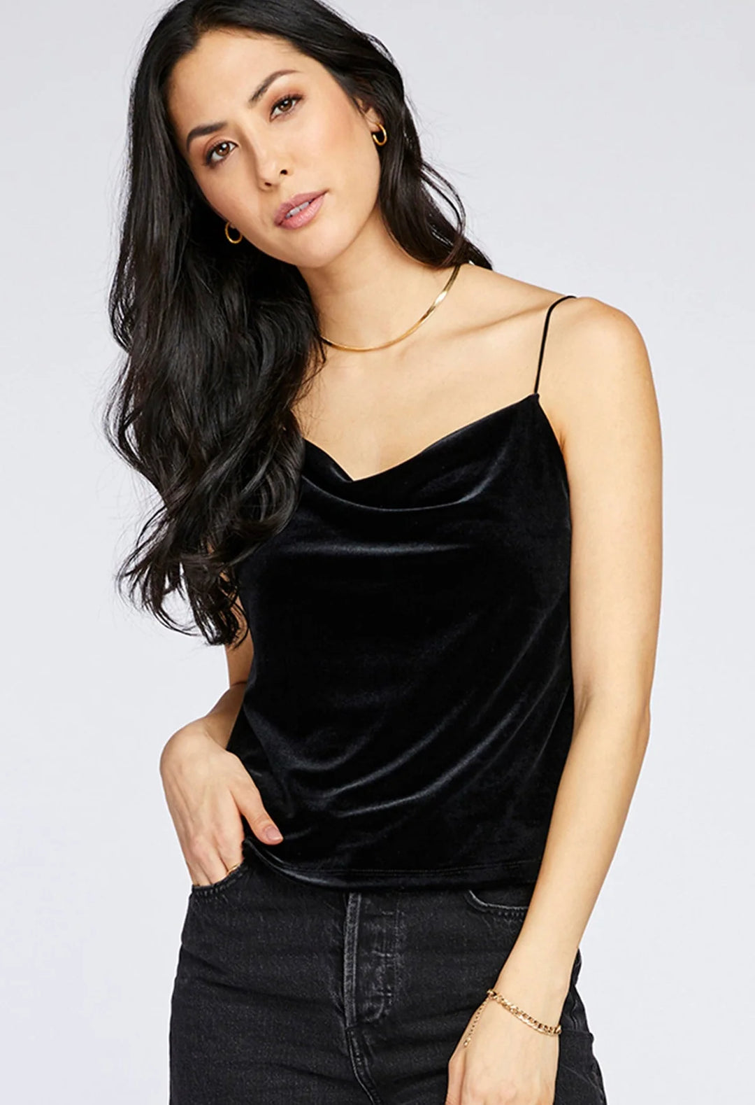 Woman wearing a black velvet top and black pants on a white background