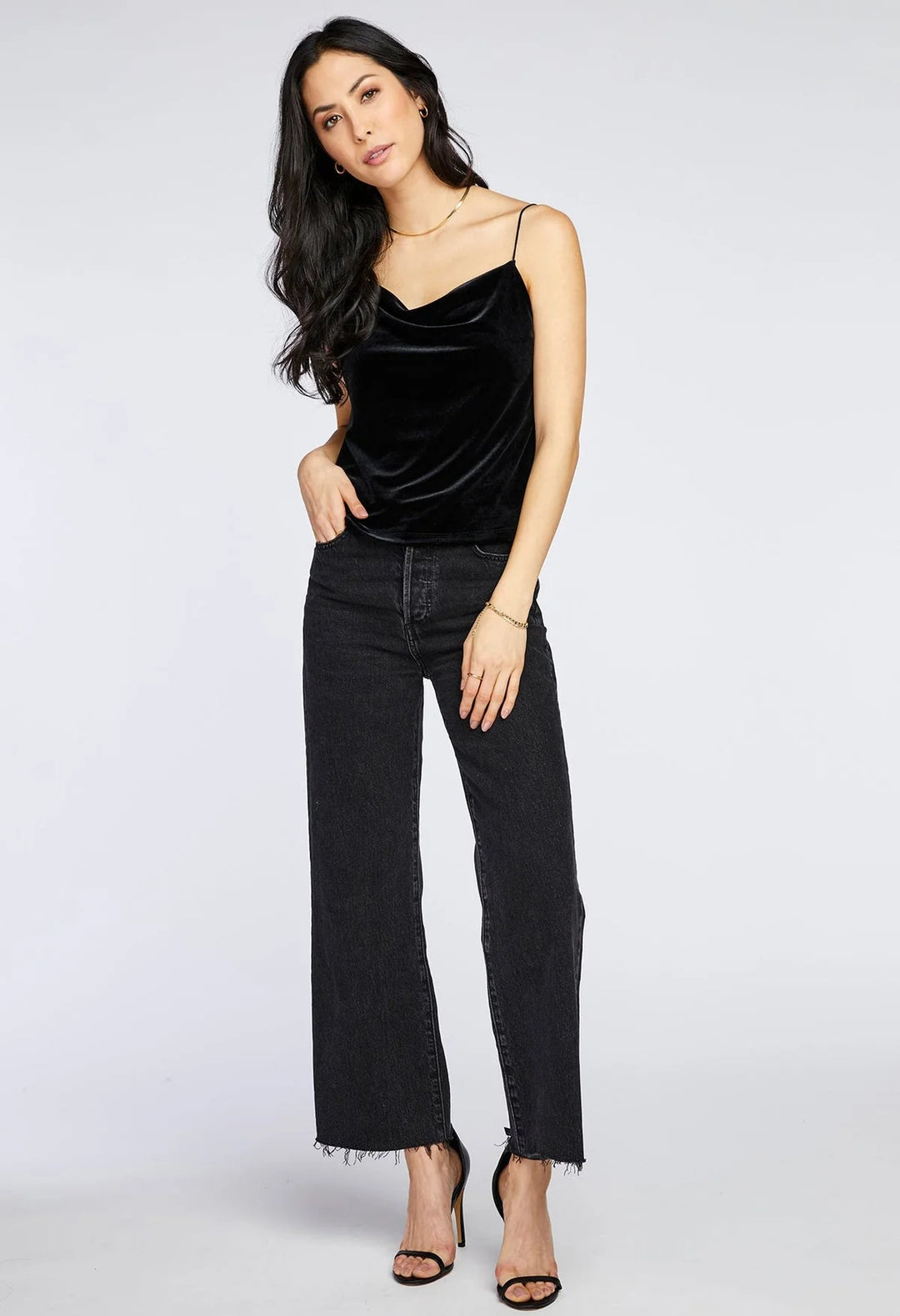 Woman wearing a black velvet top and black jeans on a white background