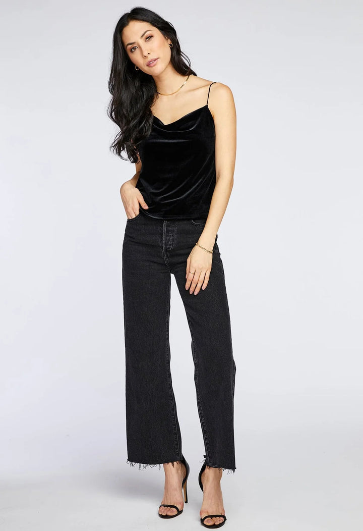 Woman wearing a black velvet top and black jeans on a white background