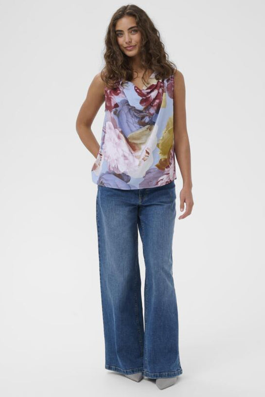 Woman wearing a floral top and blue jeans on a white background
