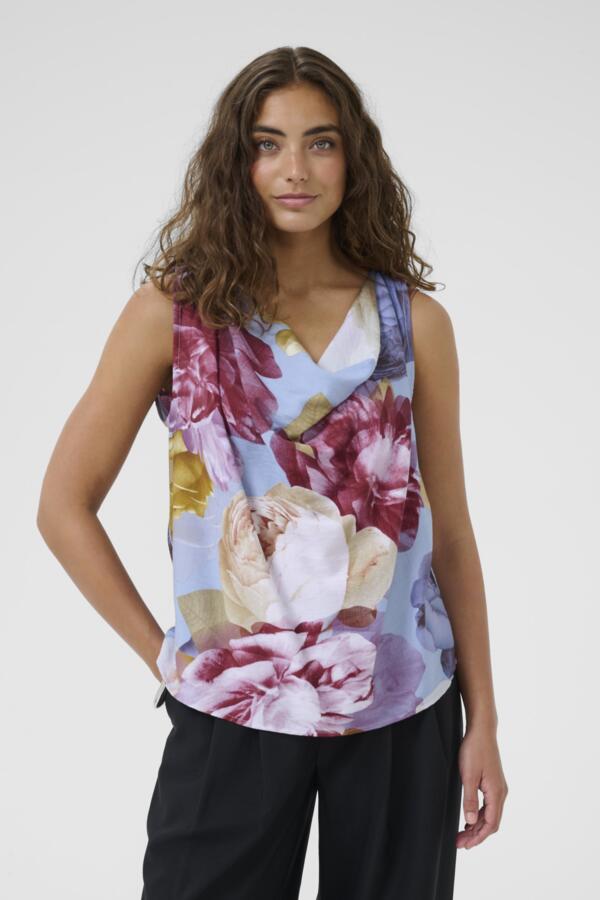 Woman wearing a sleeveless floral top against a plain background