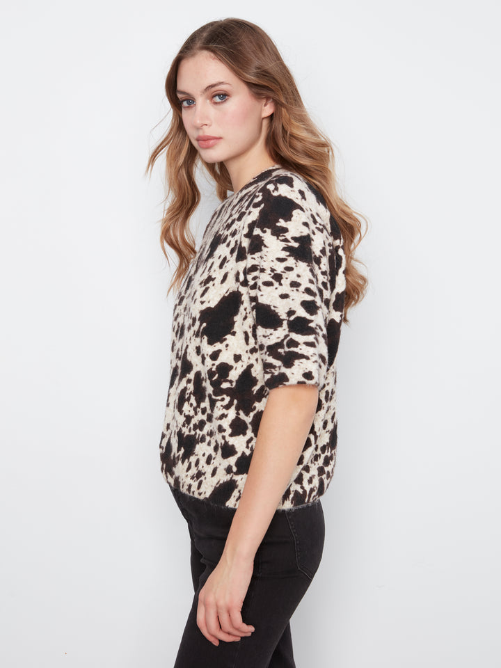 Woman wearing a black and white patterned top against a white background