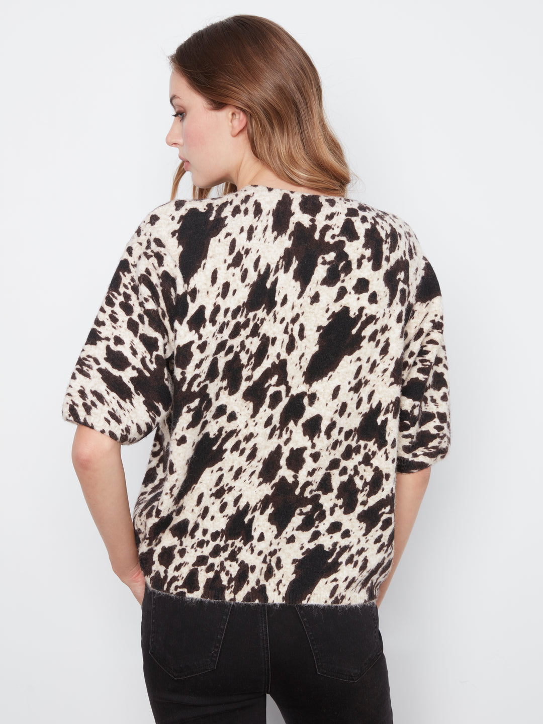 Woman wearing a black and white patterned shirt against a plain background
