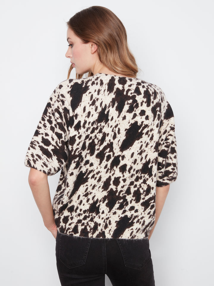 Woman wearing a black and white patterned shirt against a plain background