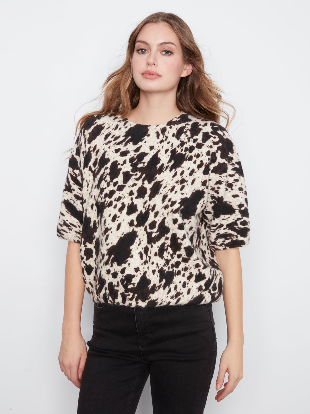 Woman wearing a patterned top with a plain background