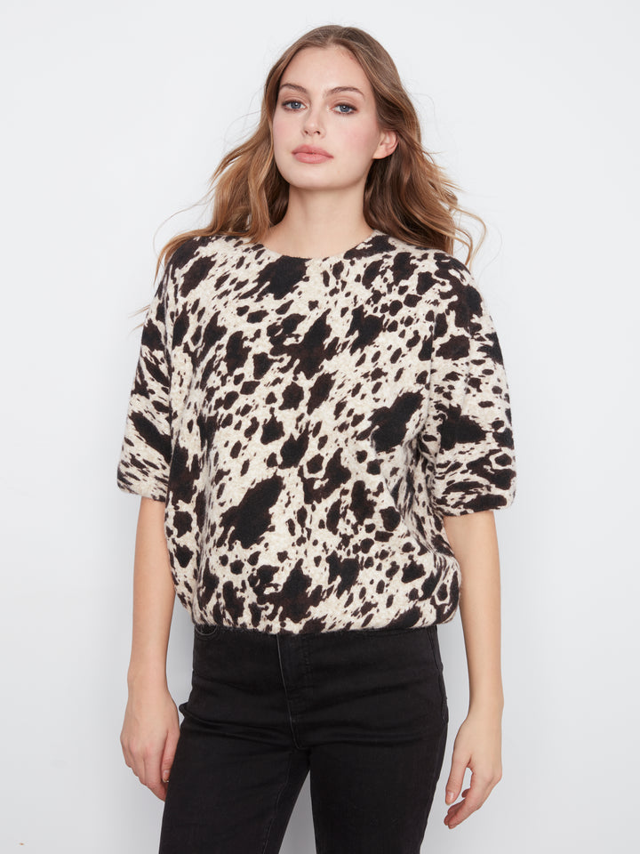Woman wearing a patterned top with a plain background
