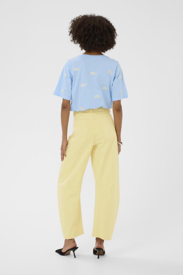 Person wearing a light blue top with cloud patterns and yellow pants on a white background
