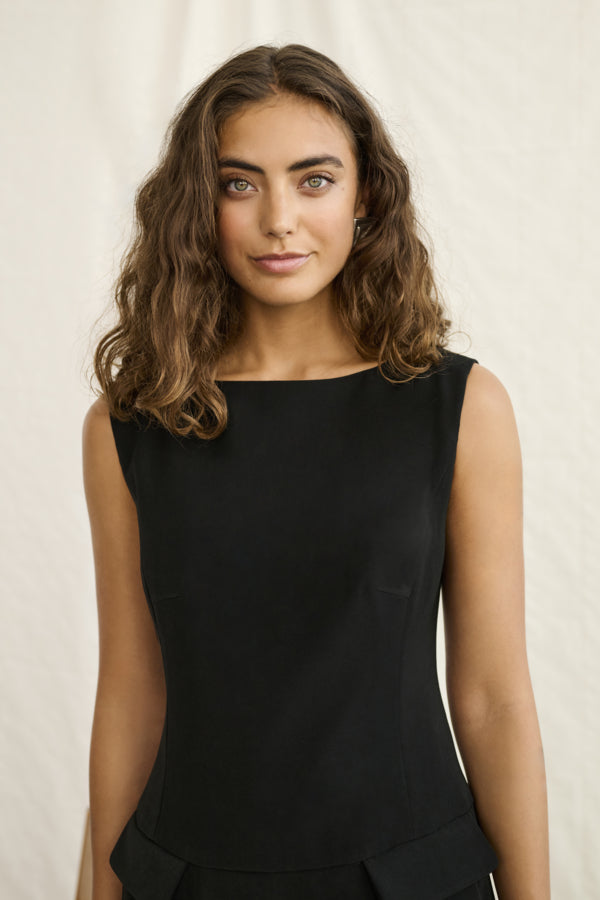 Woman wearing a black sleeveless top against a plain background