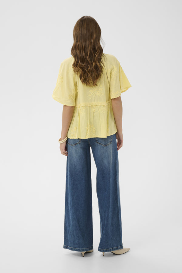 Person wearing a yellow blouse and blue jeans on a white background