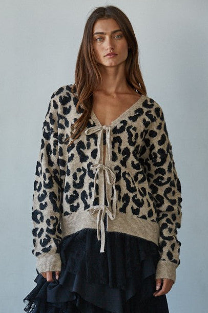 Model wearing a leopard print sweater and black ruffled skirt against a plain background