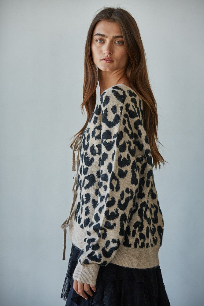 Woman wearing a leopard print sweater against a plain background