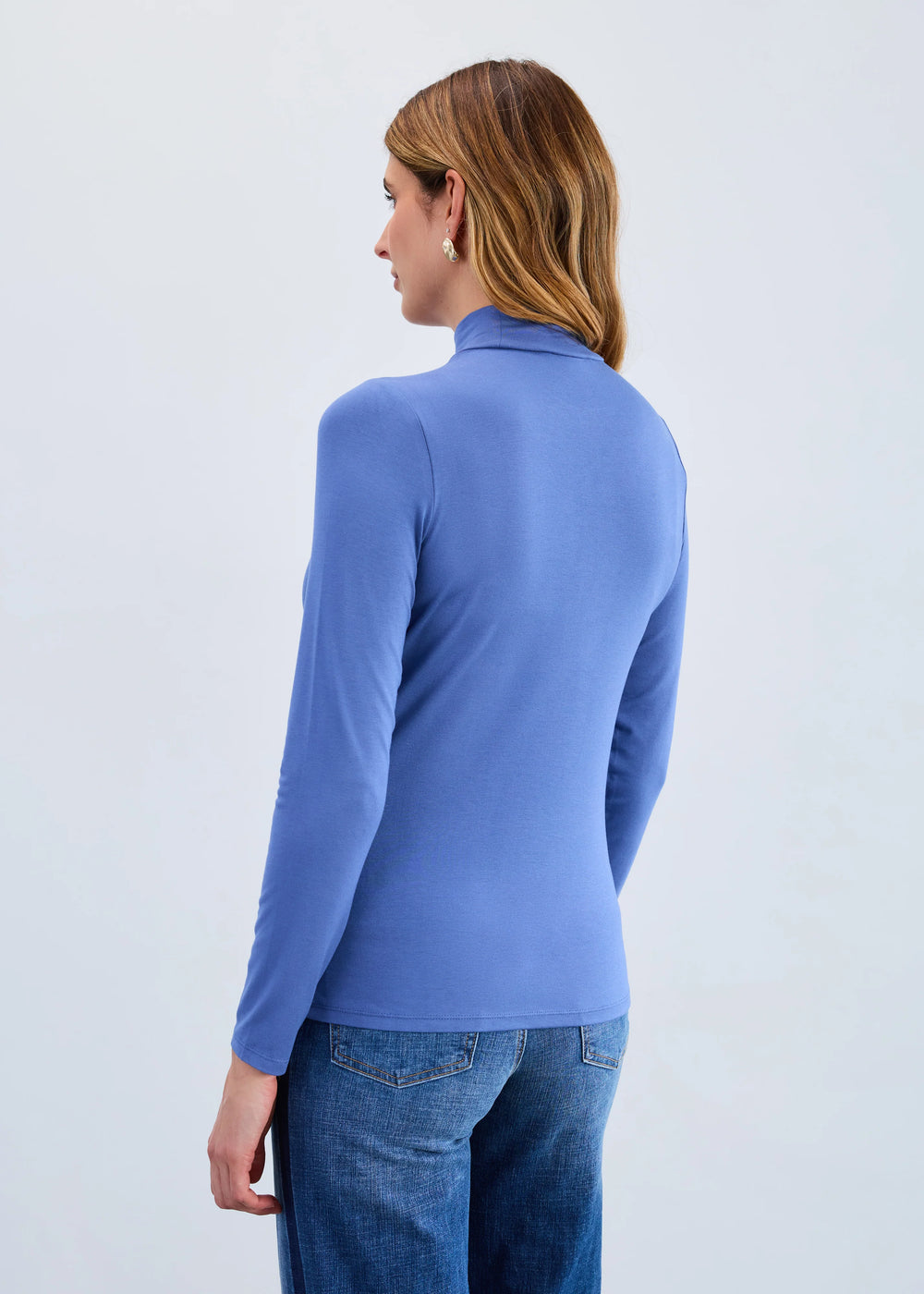 Person wearing a blue long-sleeve top against a light gray background