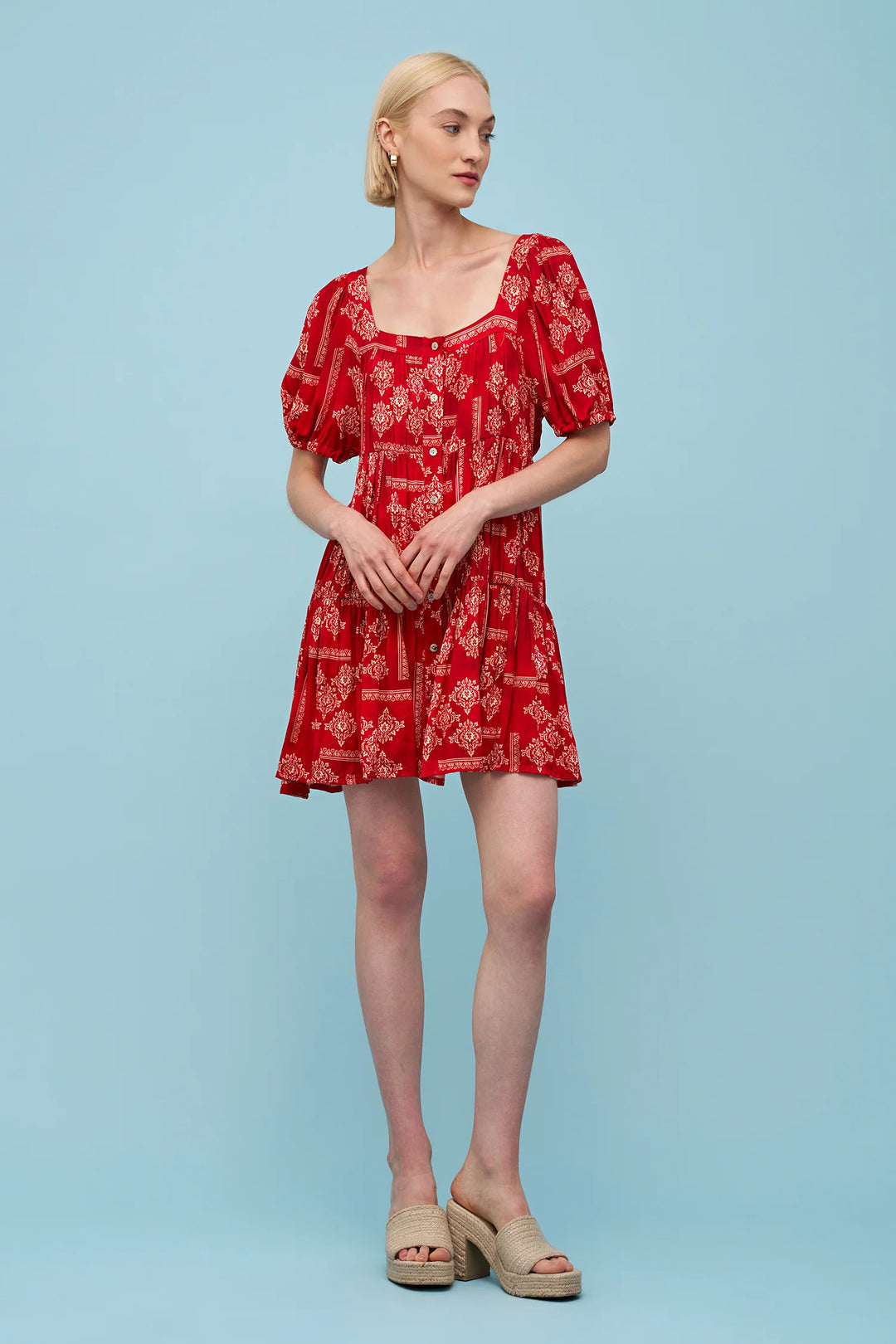 Woman wearing a red floral dress against a light blue background